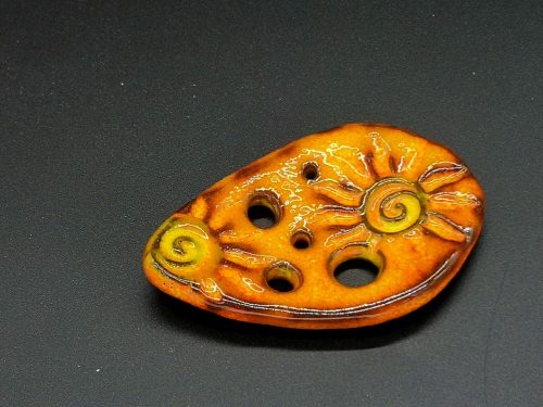 Lochscheibe aus Keramik, Relief von 2 Sonnen orangegelb lasiert mit 5 Löchern